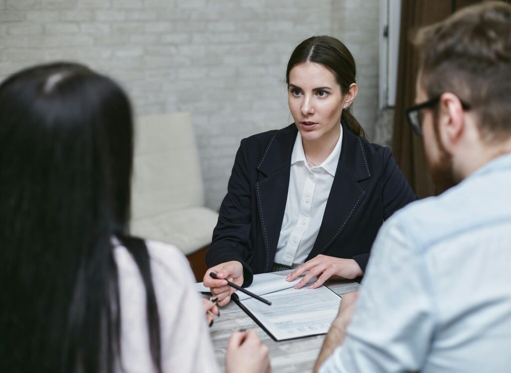 Three colleagues engaged in a business meeting discussing documents at a table indoors.