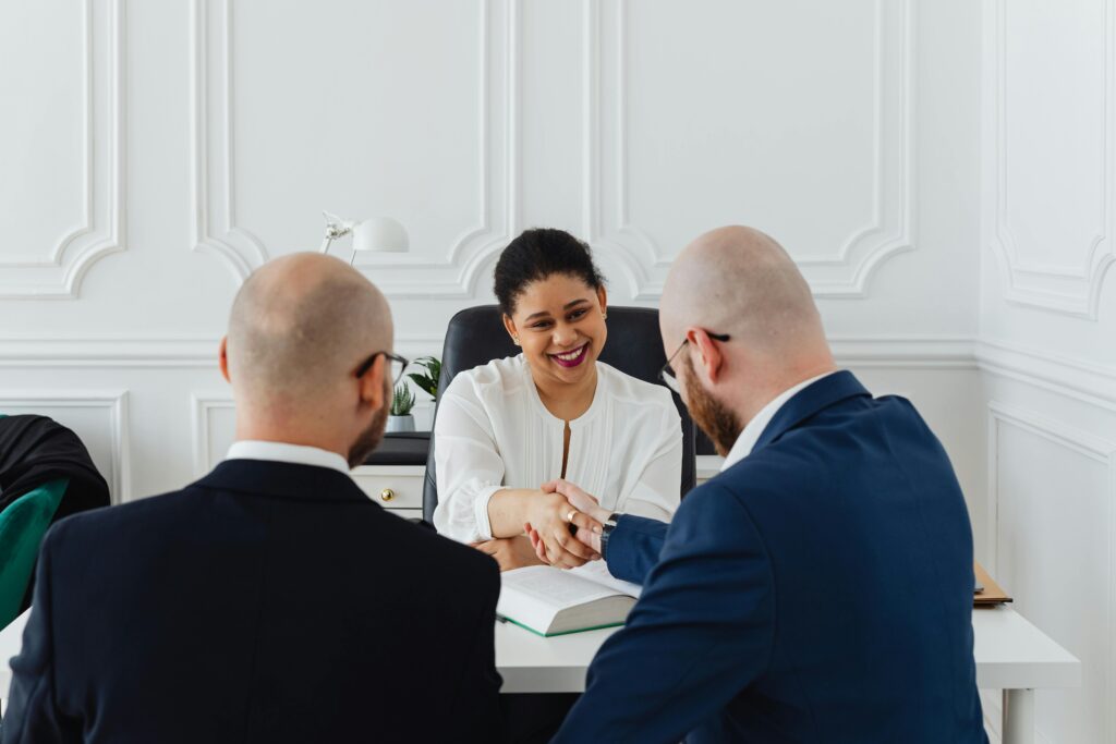 Diverse professionals in a business meeting, shaking hands across a table, indoors.