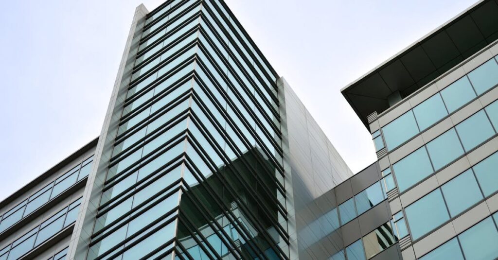 Low angle view of a modern skyscraper with glass facade reflecting the sky.