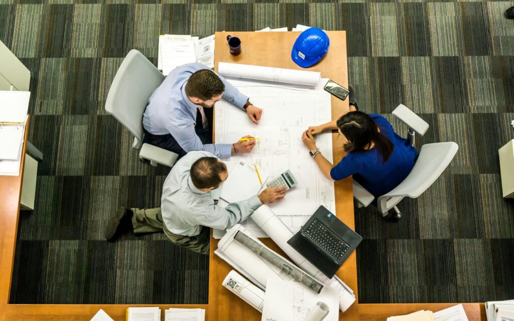 Corporate Tax Top view of a team working on construction plans in an office setting.