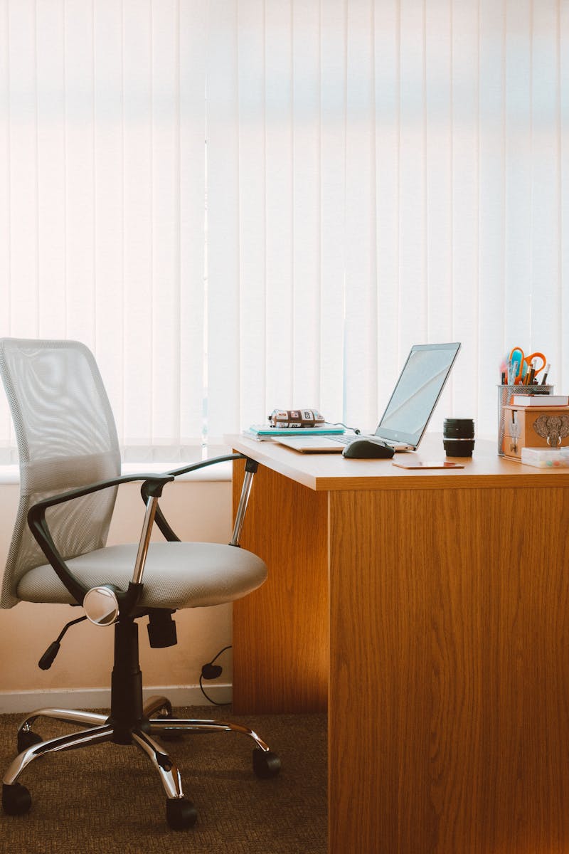 Home A tranquil modern home office featuring a wooden desk, ergonomic chair, and soft natural light.